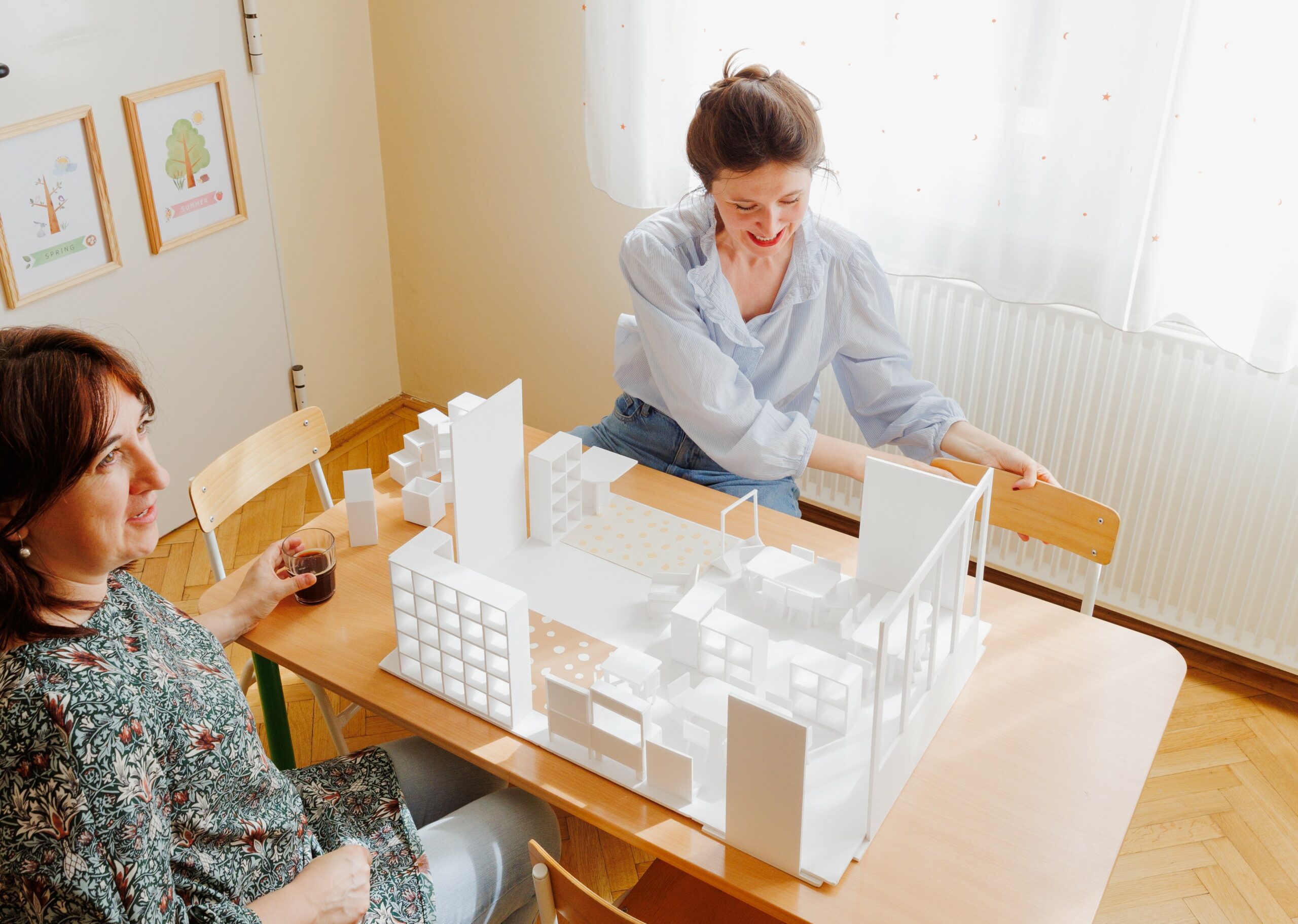 Tamara Tandara Perényi and colleague reviewing a kindergarten classroom planning mock-up at a classroom table