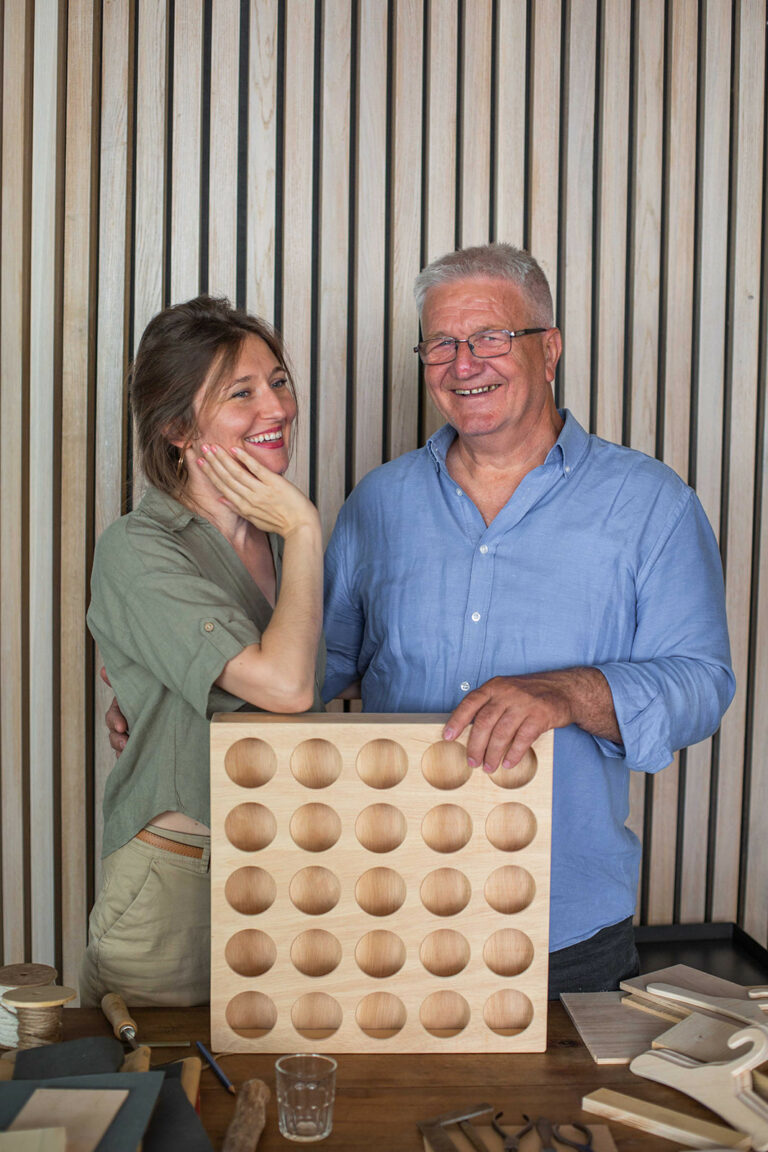 Tamara Tandara Perényi and her father holding a handmade kindergarten cup holder in a wood workshop