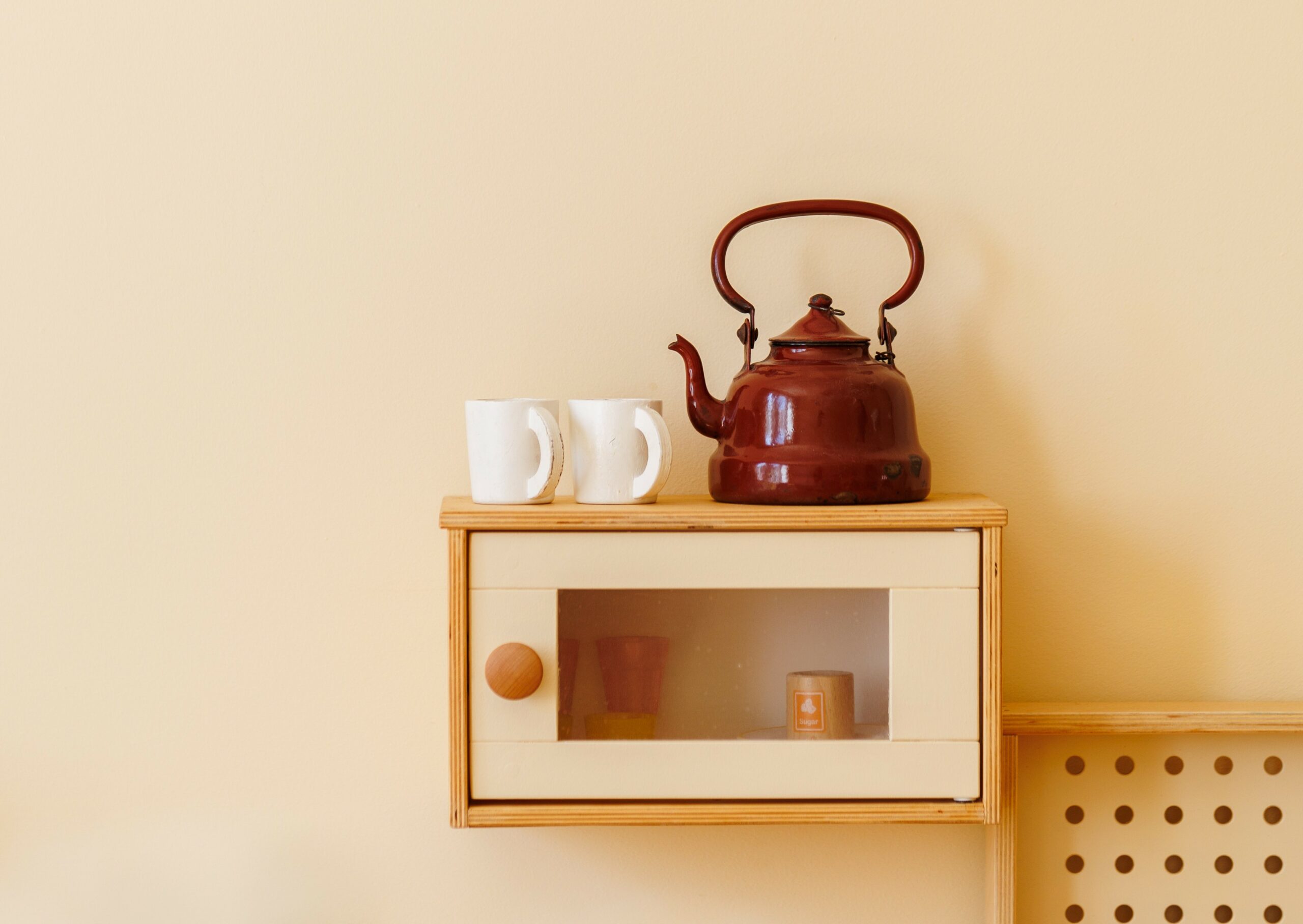 Role play learning corner showing a tea kettle and mugs, demonstrating intentional toy arrangement for imaginative play in a kindergarten classroom