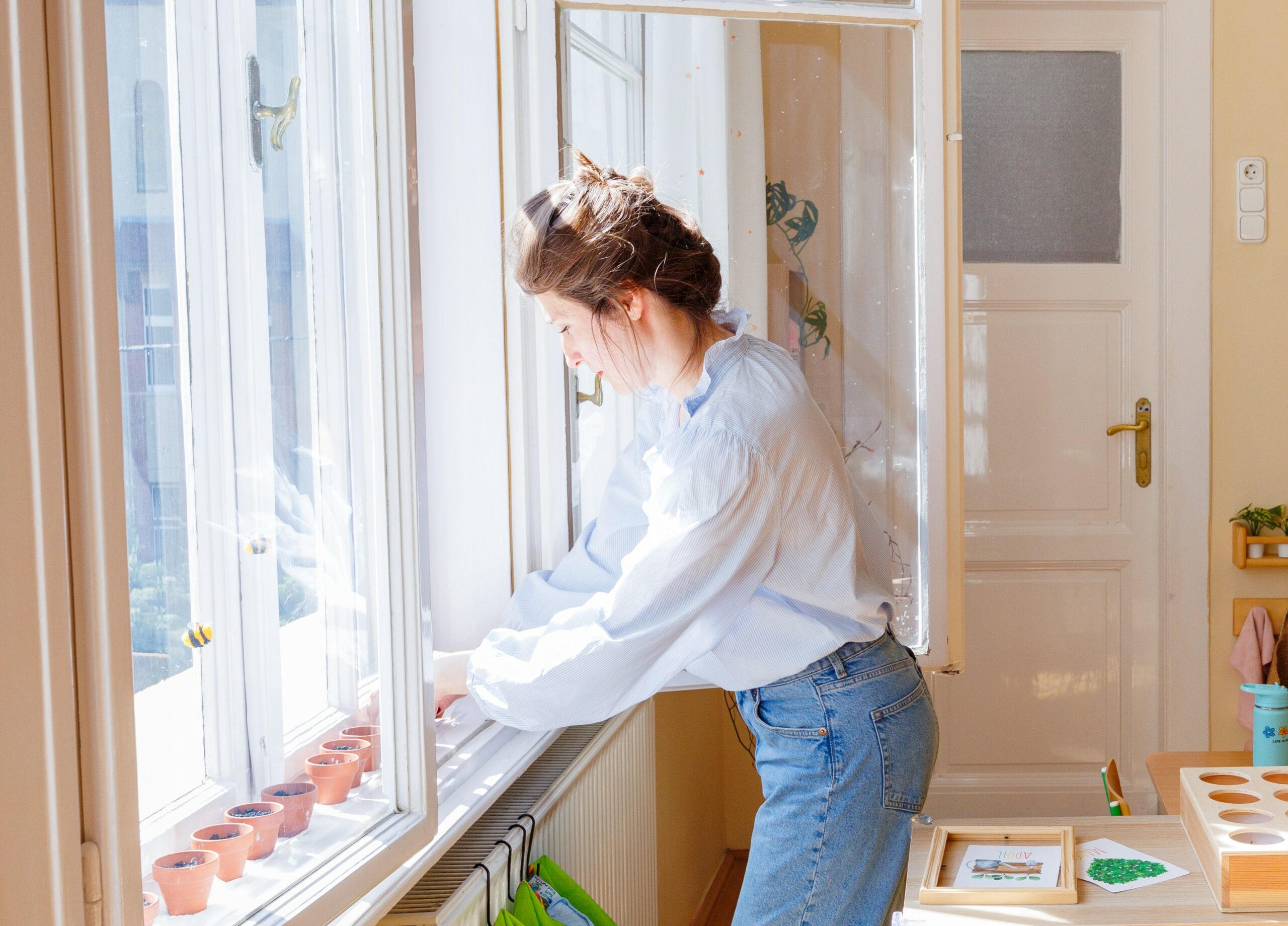 Kindergarten teacher arranging tiny flower pots, intentionally preparing classroom for an activity