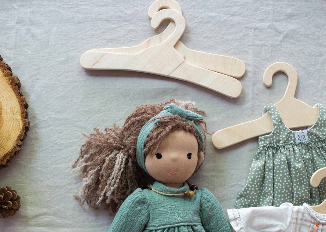 True Toys wooden hangers next to a Waldorf doll, illustrating size and intended use for doll’s clothes